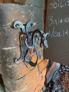 an iron gargoyle on the side of a brick wall next to a chalkboard