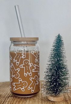 a glass jar filled with liquid next to a small christmas tree on a wooden table