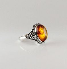 Ornated silver cognac color Amber ring with sterling silver oval shape Baltic amber jewelry cognac, ornated with vines genuine amber Classic antique style Amber ring Oval shape cabochon 925e sterling silver handmade sparkling cognac or dark green color  COLORS : the real stone color is more orange cognac then the picture Solid sterling bezel silver 925e handmade  Dimensions Stone size : 14 x 10 mm Length : 16.5 mm  Width : 18 mm  Height : 7.5 Weight : 4.7 gr Size of ring : 7.5 us,ca - 55, 56 France - P, P½ Uk sizing Classic Amber Ring Jewelry, Classic Amber Oval Cabochon Jewelry, Classic Amber Sterling Silver Ring, Classic Amber Engraved Jewelry, Formal Amber Oval Cabochon Rings, Classic Engraved Amber Jewelry, Oval Amber Cabochon Ring, Amber Oval Cabochon Rings, Classic Oval Baltic Amber Jewelry