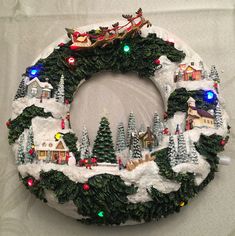 a christmas wreath made out of fake snow and lite up trees with santa's sleigh on top