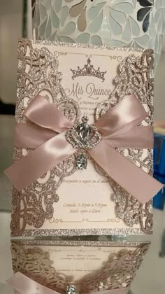 the wedding card is decorated with pink ribbon and jeweled brooches on it