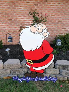 a yard decoration with a santa clause standing in front of a brick wall