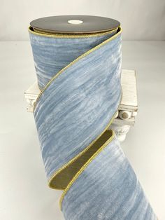 a roll of blue and gold ribbon sitting on top of a white table