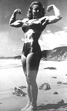 a woman standing on top of a beach next to the ocean with her arms in the air