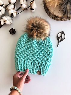 a knitted hat with a pom - pom sitting on top of it