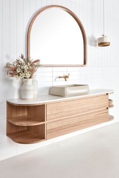 a bathroom with a sink, mirror and vase on the counter in front of it