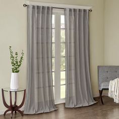 a living room with a couch, chair and window covered in gray drapes