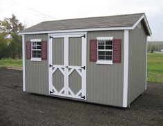 a small storage shed with shutters on the doors and windows is shown in front of a grassy field