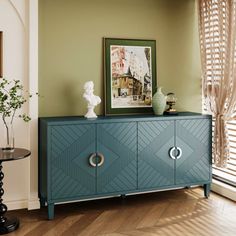 a blue cabinet in a room with a painting on the wall and a vase sitting on top of it