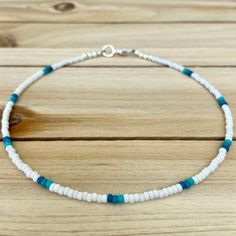 a white and blue beaded necklace on a wooden table