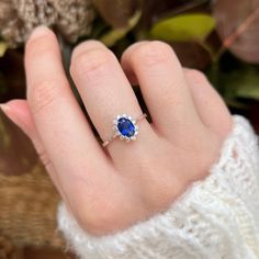 a woman's hand with a blue and white diamond ring on her left hand