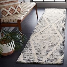 a white and black runner rug in front of a window with potted plants on the floor