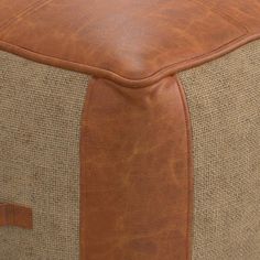 a brown and tan ottoman with leather trim