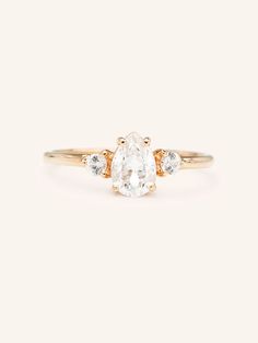 an oval cut diamond ring with three small diamonds on the band, set in yellow gold