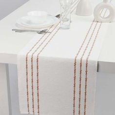 a white table with an orange stripe on it and silverware in front of it