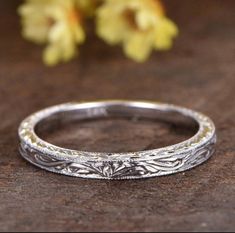 a close up view of a wedding ring on a table with flowers in the background