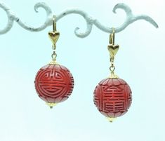 Here's a wonderful pair of vivid red Cinnabar earrings... These magnificent carved beads have traditional auspicious symbols, they measure about 16 mm diameter. Yellow gold-filled caps on the top and bottom create the perfect contrast with the intensely red gem beads! Gold filled lever backs have decorative hearts on the front, latch closed for security, and are in perfect original condition, stamped 1/20 14K GF. From top to bottom these earrings hang a total of about an inch and 1/2 long.  ~ These will arrive at your house Gift Boxed, ready to giftwrap or wear! ~ you can also find, LIKE & follow Squidnuggets on Instagram for first looks at new work!! Traditional Red Pierced Earrings, Red Carved Jewelry Gift, Red Carved Jewelry For Gifts, Earrings Asian, Decorative Hearts, House Gift Box, Gem Beads, Asian Design, Red Beads