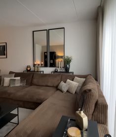 a living room with couches and mirrors on the wall above them is lit by candles