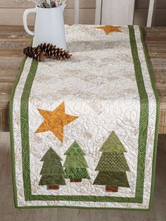 a table topped with a white vase filled with flowers and a quilted table runner