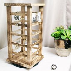 a wooden jewelry stand next to a potted plant