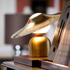 a clock that is sitting on top of a wooden stand with a hat on it