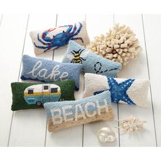 four beach themed pillows on a white wooden surface