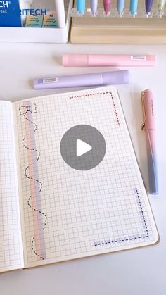 an open notebook sitting on top of a table next to markers and pens, with a video playing in the middle