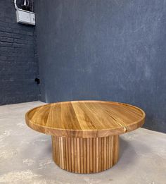 a round wooden table sitting on top of a cement floor