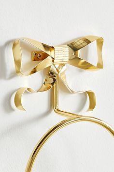 a close up of a gold bow tie on a white wall with a circular object in the foreground