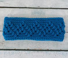 a blue crocheted headband sitting on top of a wooden table