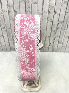 a pink ribbon with white lace and flowers on it