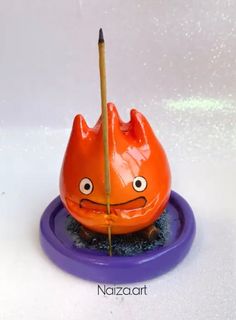 an orange object with eyes and a pencil sticking out of it's mouth on a purple plate