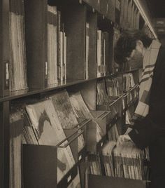 a man standing in front of a bookshelf filled with lots of records and cds