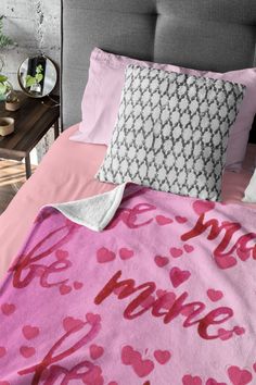 a bed covered in pink sheets and pillows with the words love written on each pillow