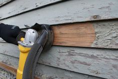 a yellow and black hose is attached to the side of a house with wood siding