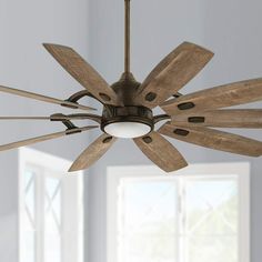 a ceiling fan with wooden blades in a room