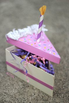 a birthday cake box with a single candle sticking out of it's top and sprinkles on the inside