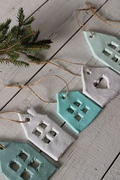 three blue and white ceramic house ornaments hanging from twine strings on a wooden table