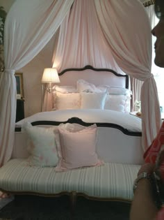 a bed with white sheets and pink pillows