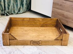 a wooden tray with the name majore on it sitting on a floor next to a dresser