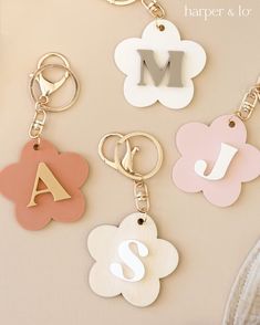 four different types of keychains with the letter m on one side and flower on the other