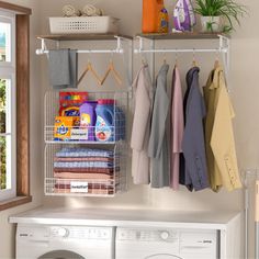 an organized laundry room with clothes hanging on the rack and washing machine next to it