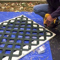 a man is using a drill to fix a hole in the ground that has been placed on top of a blue tarp