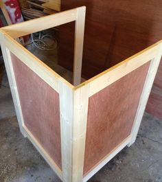 a large wooden box sitting on top of a floor next to a pile of wood