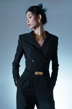 a woman in a pinstripe suit and gold necklace