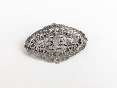 Showcase a touch of Gallic style flair with this elegant 'A Ma Vie' brooch, a patriotic emblem of French Brittany. Crafted in the 1800s during the Victorian era, this accessory is designed with an intricate silver filigree coat of arms, beautifully encapsulated within an oval crest shield. A stunning piece of historical jewellery, the brooch encapsulates Bretagne's rich cultural heritage. Fastens with a trombone 'push-pull' backing pin fastening, unbranded, no hallmarks (acid tested). A remarkab