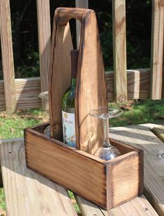 a wooden box with a wine glass and bottle in it sitting on a picnic table