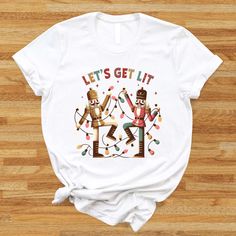 Celebrate the season in style with this Retro Christmas Nutcracker Shirt! Featuring a fun "Let's Get Lit" design with festive lights, it's perfect for Christmas parties, family gatherings, or as a unique winter gift. Spread holiday cheer with this merry and bright tee! 🎅✨ 🌟 Welcome to BLG Design Lab! 🌟 We are a small family business dedicated to crafting custom designs on high-quality t-shirts, sweatshirts, long sleeves, tank tops, V-necks, youth and toddler shirts, babysuits, tote bag and towels. Our goal is to provide you with unique, stylish, and comfortable apparel that you'll love. Why Choose Us? 💎 Premium Quality: We use top-quality materials and DTF technology for vibrant, long-lasting prints. 🎨 Unique Designs: Each design is created with attention to detail and personalized ju Nutcracker Shirt, Lets Get Lit, Christmas Party Gift, Wedding Gift Baskets, Christmas Parties, Winter Gift, Nutcracker Christmas, Christmas Light, Design Lab