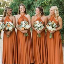 a group of women standing next to each other wearing orange dresses and holding bouquets