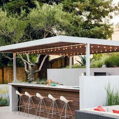 an outdoor kitchen with bar seating and lights